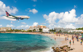 Delta flight approaches St Maarten&#39;s Princess Juliana Airport above onlookers on Maho Beach
