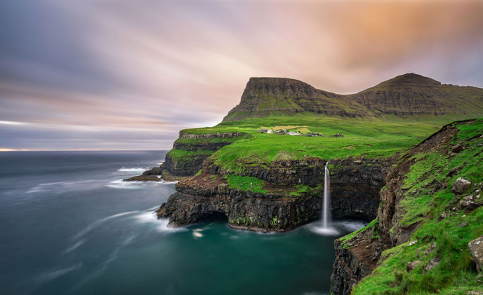 Gasadalur village and its iconic waterfall, Vagar, Faroe Islands, Denmark. Long exposure. (photo via miroslav_1 / iStock / Getty Images Plus)