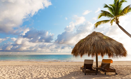 Beach chairs with umbrella and beautiful sand beach in Punta Cana, Dominican Republic (Photo via Preto_perola / iStock / Getty Images Plus)
